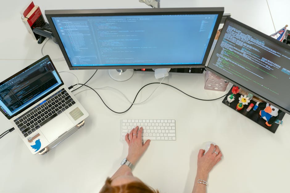 Female software engineer coding on dual monitors